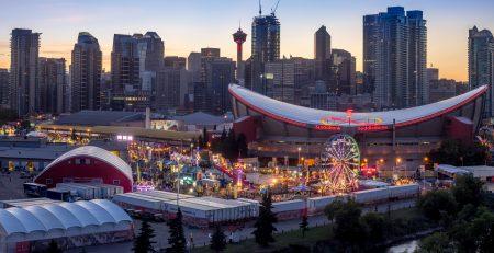 Calgary Stampede carnival area with Saddledome behind it. Calgary tower and Calgary downtown in the background.