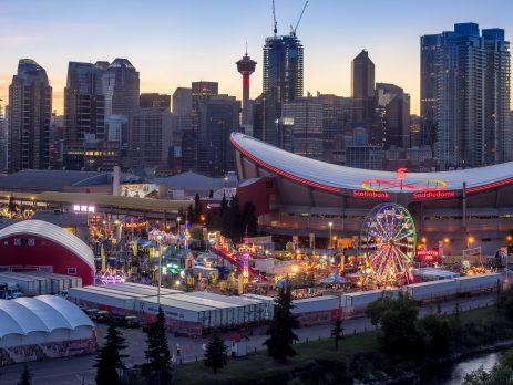 Calgary Stampede carnival area with Saddledome behind it. Calgary tower and Calgary downtown in the background.