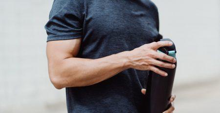 Fit male wearing blue shirt holding a reusable water bottle
