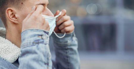a man putting on a surgical style mask