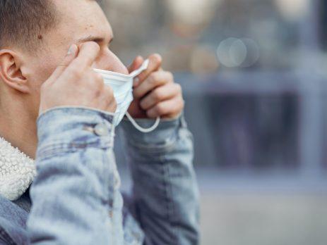 a man putting on a surgical style mask