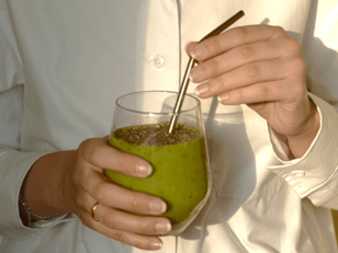 Clear glass with green health drink inside. metal straw