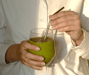 Clear glass with green health drink inside. metal straw