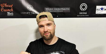 Olson Werenka holding a fit kitchen meal wrapped in plastic with a label