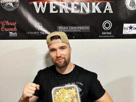 Olson Werenka holding a fit kitchen meal wrapped in plastic with a label